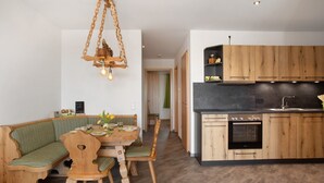 Cuina moderna amb armaris de fusta, forn integrat i zona de dinar amb taula i banc de fusta.