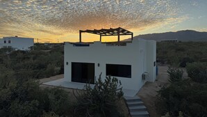 Un edificio moderno blanco con techo plano y estructura de pérgola de madera.