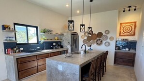 Una cocina moderna con una isla grande, armarios de madera e iluminación colgante.