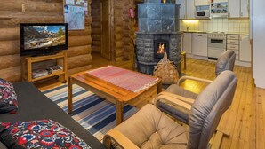 Un intérieur chaleureux de chalet en bois, avec une cheminée, un téléviseur et un coin repas.
