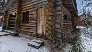 Une cabane en rondins avec une porte en bois, un porche et un petit escalier menant à l’entrée.