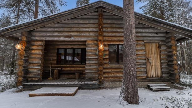 Une cabane en rondins avec une véranda, un banc et une porte en bois.