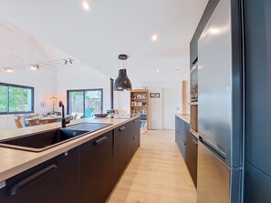 A modern kitchen with dark cabinetry, a large island, and a built-in oven.