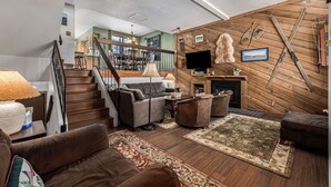 Ein geräumiges Wohnzimmer mit Kamin, Holzwänden und einer Treppe zu einer oberen Etage.