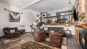 Ein Wohnzimmer mit Kamin, einer Treppe und einem Essbereich mit Stühlen und Tisch.