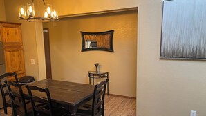 A dining area with a wooden table and chairs, a chandelier, a small side table with a vase, and a framed mirror on the wall. - Spacious 5-bedroom house with WiFi, AC in charming Arvada (Arvada)