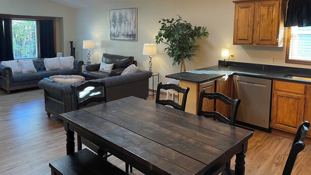 A modern living room with a dark wood dining table, a leather sofa, and a chandelier. - Spacious 5-bedroom house with WiFi, AC in charming Arvada (Arvada)