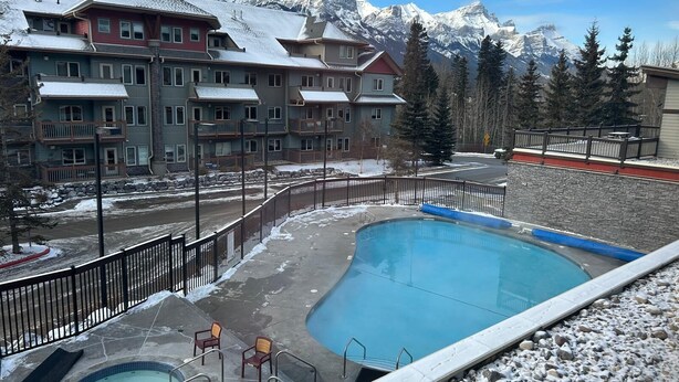 Un hotel con piscina, mobiliario exterior y vistas a montañas nevadas.