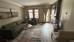 Una sala de estar con sofá, sillón, mesa de centro y chimenea.