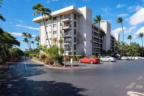 Un hotel moderno con diversi piani, balconi e un'area parcheggio con diverse auto.