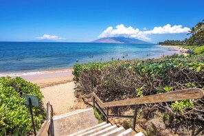 Ein Strand mit einer Treppe, die zum Ufer führt, umgeben von viel Grün.