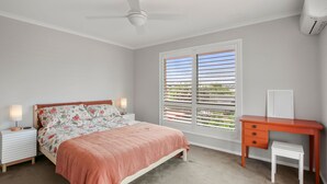 A bedroom with a bed, bedside lamps, a desk, and a window with blinds. - Bren Place, 6, Battery Hill (Battery Hill)