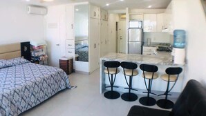 A compact living space with a bed, kitchenette, and a dining area with bar stools. - Area Ocean, Affordable 1BR Studio, Beachfront Resort, Pools, Snack Bar, & Balcony (Nuevo Vallarta)