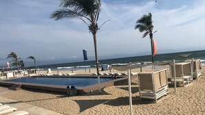 A beachside pool area with lounge chairs and a small pool. - Area Ocean, Affordable 1BR Studio, Beachfront Resort, Pools, Snack Bar, & Balcony (Nuevo Vallarta)