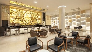 Un moderno vestíbulo de hotel con zona de bar, arreglos de asientos y una pared decorativa.