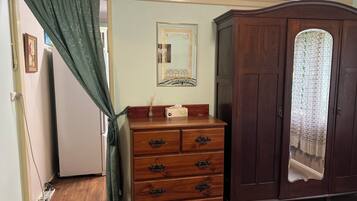 A room with a wooden dresser, a mirror, and a wardrobe.