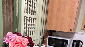 Uma cozinha com micro-ondas, torradeira e um vaso de flores sobre uma bancada de mármore.