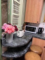 Una cocina con microondas, tostadora y un florero sobre una encimera de mármol.