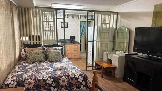 Quarto com cama, escrivaninha, televisão e guarda-roupa.