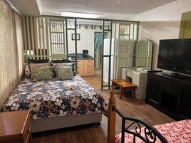 Un dormitorio con cama, escritorio, televisor y armario.