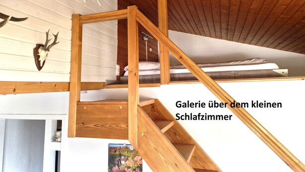 Ein kleiner Schlafraum mit einer Holztreppe und einer Deckenleuchte.