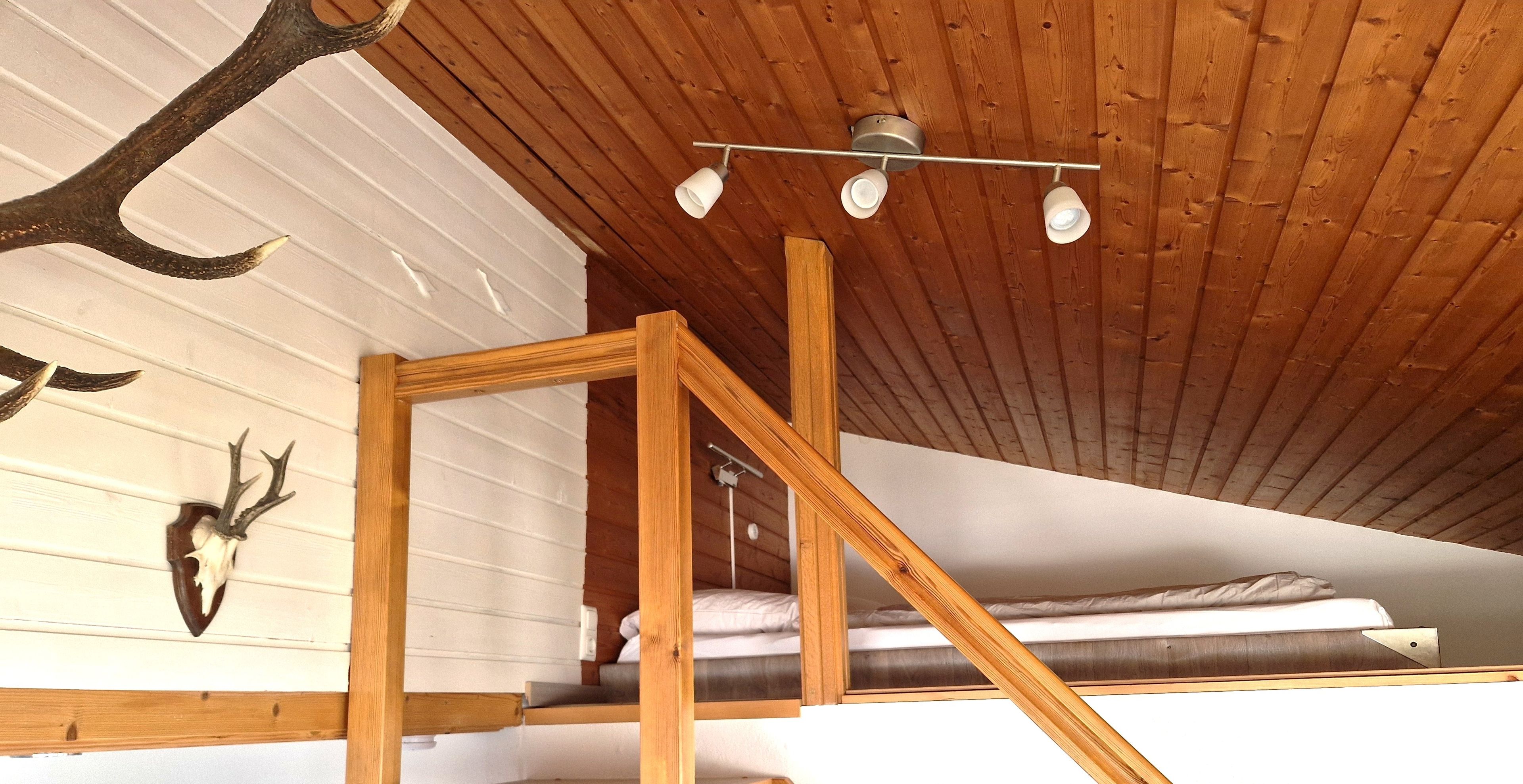 A small sleeping area with a wooden staircase and a ceiling light fixture.