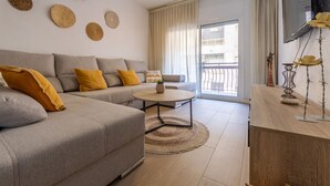 Un salon moderne avec un canapé gris, des coussins jaunes, une table basse ronde et un ventilateur de plafond.