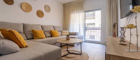 A modern living room with a grey sofa, yellow cushions, a round coffee table, and a ceiling fan.