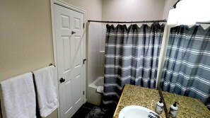 A bathroom with a white door, a shower curtain, a sink with a granite countertop, and two bottles on the counter. - Classic 3BD 3BTH at Moose Hollow, view of Mtns (Eden)