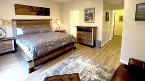 A bedroom with a bed, bedside tables, a dresser, a rug, and a hallway leading to another room. - Classic 3BD 3BTH at Moose Hollow, view of Mtns (Eden)