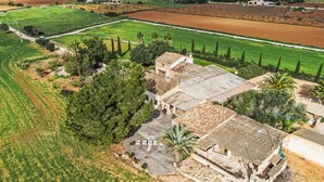 Vista aérea de una propiedad rural con un amplio patio descubierto, rodeado de campos y árboles.
