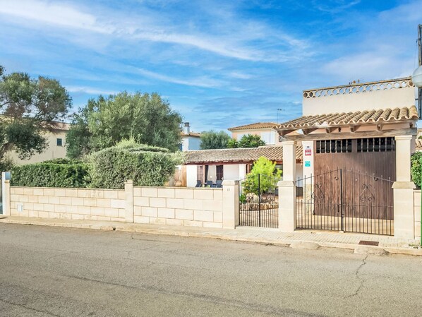 A residential property with a gated entrance, a tiled roof, and a brick wall.