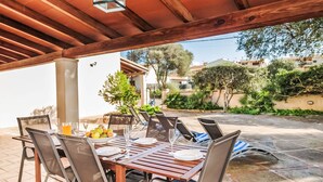 An outdoor patio with a wooden table and chairs, a bowl of fruit, and a glass of orange juice. - Villa Sa Rapita by Interhome (Sa Rápita)