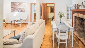A modern living room with a sofa, a dining table with chairs, a fireplace, and a painting on the wall. - Villa Sa Rapita by Interhome (Sa Rápita)