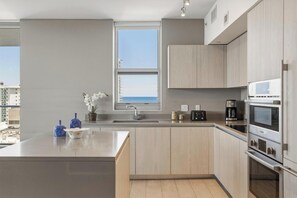 Una cocina moderna con una isla grande, electrodomésticos integrados y vista al mar.
