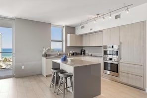 Una cocina moderna con una isla grande, taburetes de bar y vistas al océano.