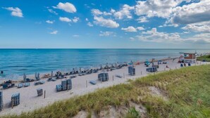 A beach with rows of striped beach chairs and umbrellas, a lifeguard tower, and a clear view of the ocean.