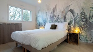 A bedroom with a bed, a nightstand, a window, and a wall with a leaf pattern. - Cottage Brocéliande * SPA * Terrace * Location * (La Gacilly)