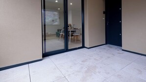 A modern building exterior with a sliding glass door leading to an interior dining area. - Cottage Brocéliande * SPA * Terrace * Location * (La Gacilly)