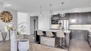 A modern kitchen with a central island, bar stools, and pendant lighting.