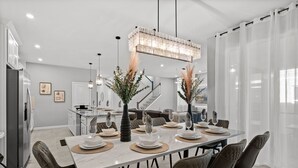 A modern dining area with a marble table set for six, surrounded by leather chairs.