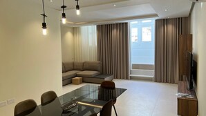 Una sala de estar moderna con una mesa de vidrio para comer, un sofá y un televisor.