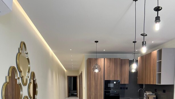 Una cocina moderna con armarios de madera, una isla central con taburetes e iluminación colgante.