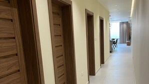 Un pasillo con puertas de madera y suelo de baldosas blancas.