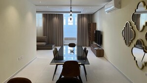 Una sala de estar moderna con comedor, ventanas amplias y vistas al exterior.