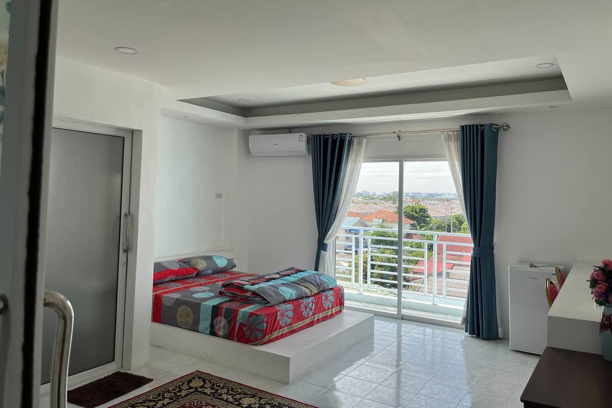 A bedroom with a bed, a desk, and a view of the city.