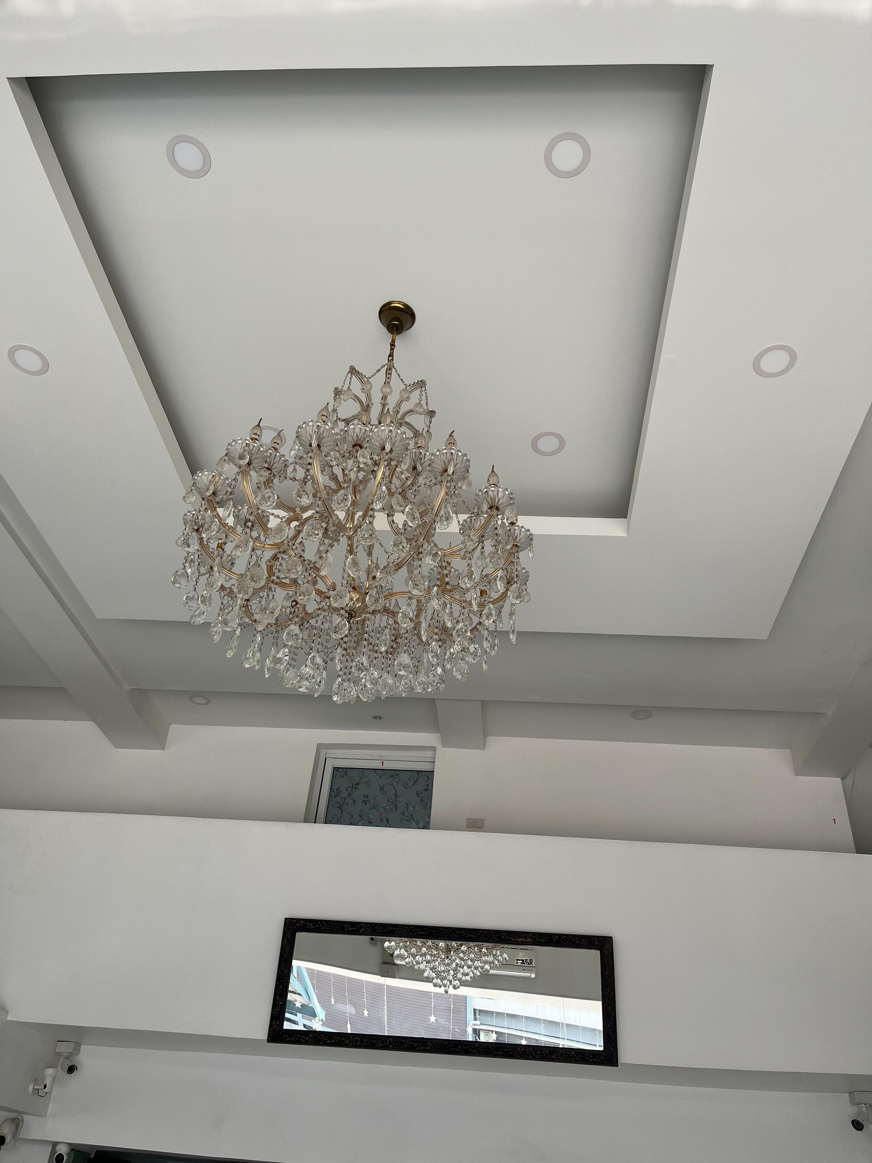 Un interior moderno con una lámpara decorativa, luces empotradas en el techo y un cuadro enmarcado en la pared.