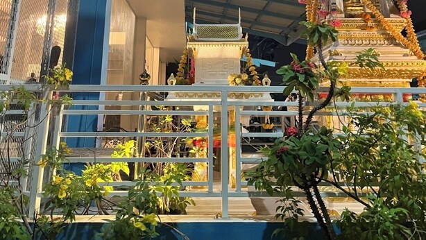 A temple with a golden spire, surrounded by a white fence and potted plants. - Alisara Apartments (Bangkok)