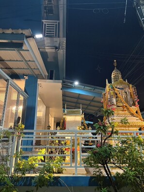 Un temple surmonté d’une flèche dorée, entouré d’une clôture blanche et agrémenté de plantes en pot.