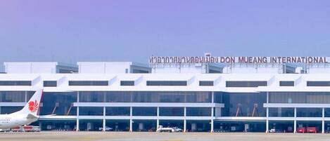 A modern airport terminal with a clear sign reading "Don Mueang International".